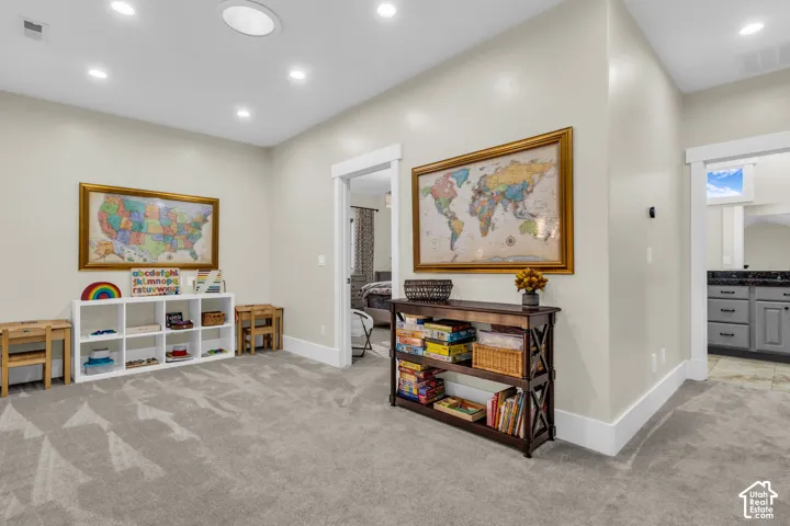 Spacious carpeted room featuring recessed lighting, a built-in shelving unit, and white trim molding