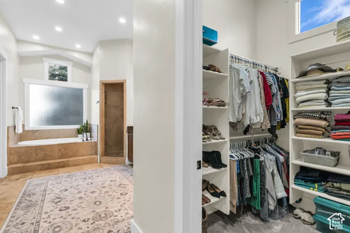 Walk-in closet featuring built-in shelving, hanging rods, and a high window
