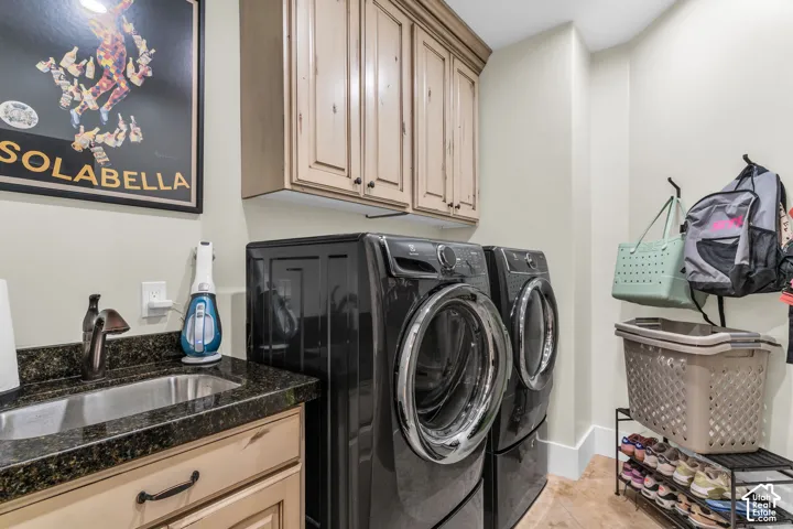 Utility room featuring a utility sink, dark granite-style countertop, and light wood-finish cabinetry