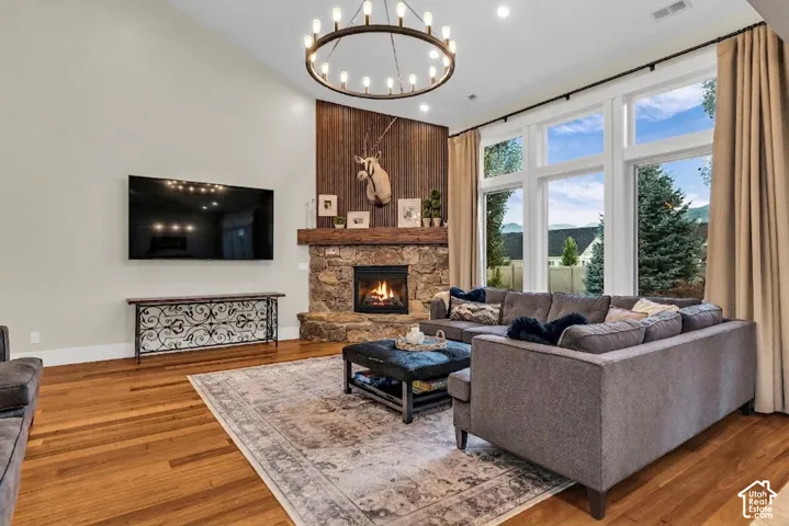 Living area featuring a stone fireplace with a wood-plank accent wall, vaulted ceilings, and a large chandelier