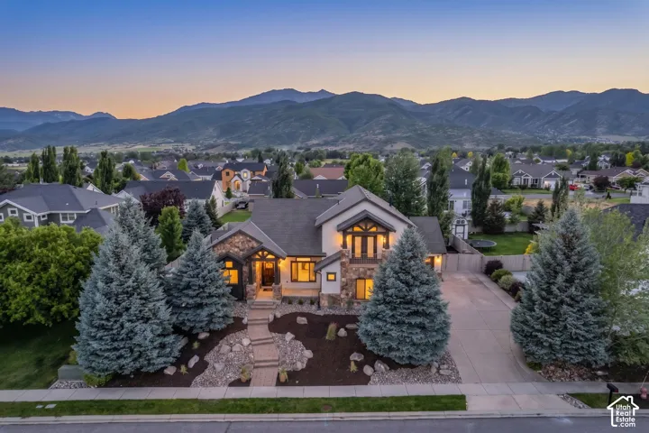 Two-story residence featuring stone and stucco exterior, multiple gables, and an attached two-car driveway