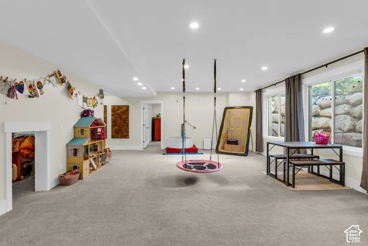 Spacious carpeted room featuring recessed lighting, multiple windows with curtains, and a white trim baseboard