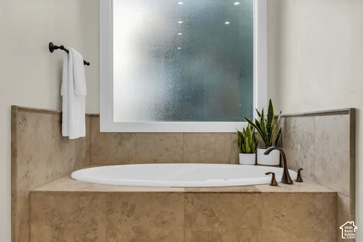 Built-in soaking tub with a tiled surround, frosted window, and bronze-finish fixtures