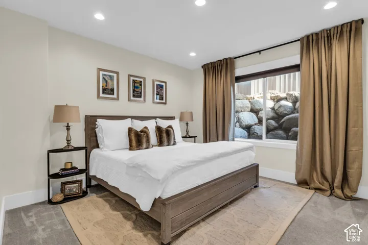 Spacious bedroom featuring recessed lighting, light-colored walls, and a large window with a stone rock feature