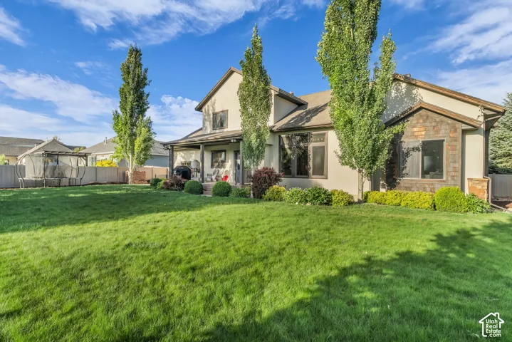 Expansive rear yard with a manicured lawn, established landscaping, and mature trees