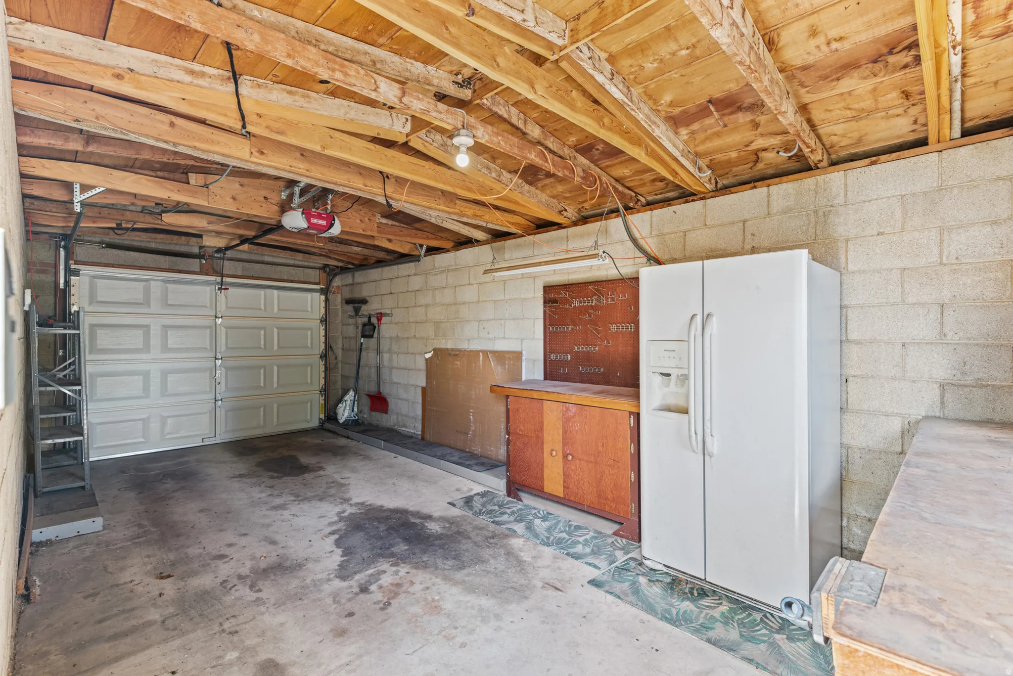 Single-bay garage with concrete block walls, exposed wood beam ceiling, and a paneled garage door