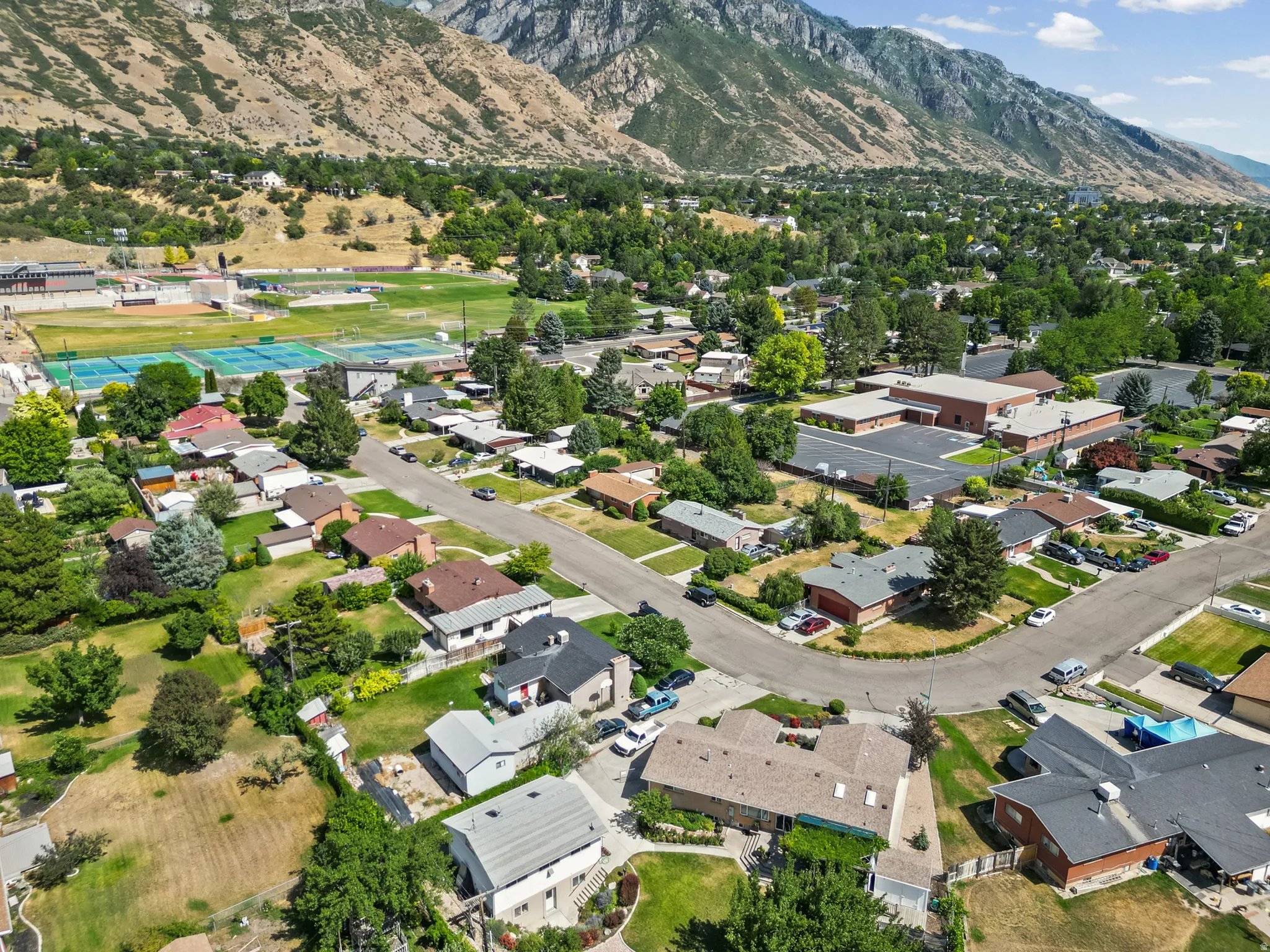 Aerial perspective showcasing a residential area with diverse home styles, mature trees, and mountainous terrain