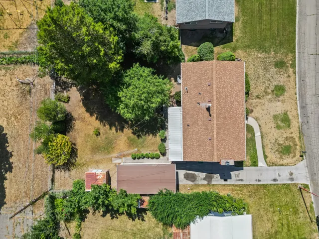 Aerial property view featuring a brown shingle roof, a paved driveway, and a concrete walkway