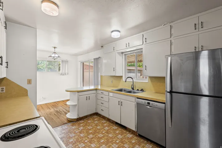 Kitchen with white cabinetry, light countertops, and a dual-basin sink with a gooseneck faucet