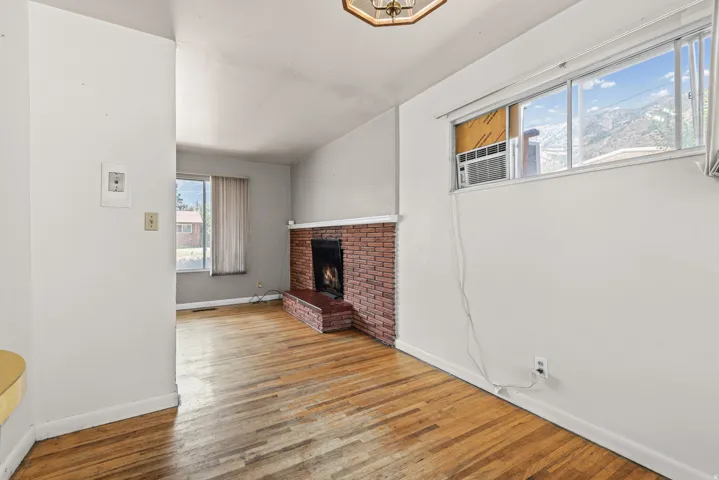 Living room featuring wood-finish flooring and a brick fireplace with hearth