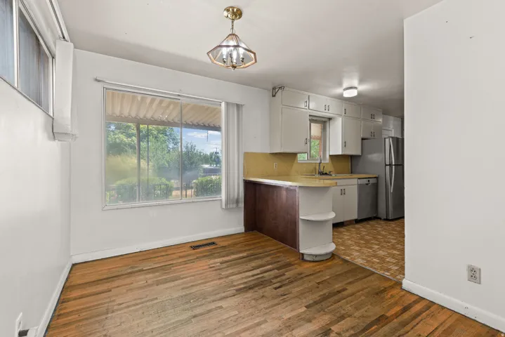 Dining area with wood-finish flooring, a large window, and an overhead light fixture
