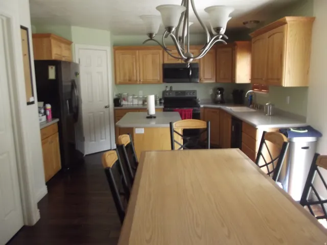 Kitchen with wood-finish flooring, light wood cabinetry, and a central island with countertop seating