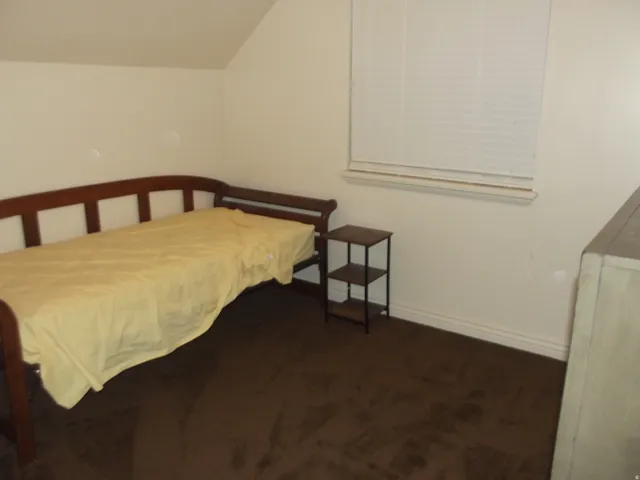 Carpeted interior space featuring neutral wall tones and a window with horizontal blinds