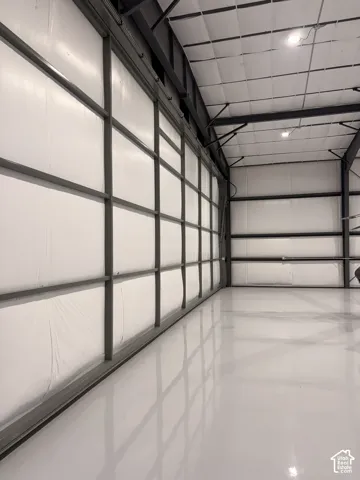 Large industrial interior featuring a high, insulated ceiling, bright white epoxy flooring, and a expansive wall of framed translucent panels
