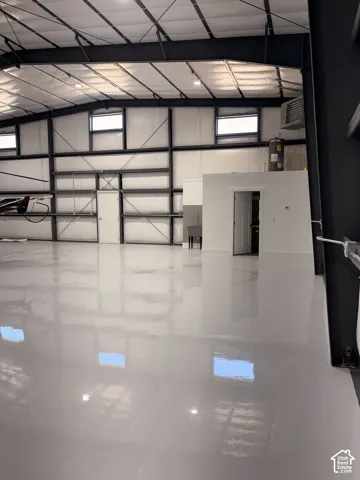 Spacious interior featuring a polished concrete floor, exposed structural steel beams, and insulated wall panels