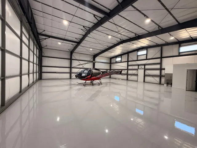 Spacious hangar featuring a high-gloss, light gray epoxy floor and exposed metal beam construction