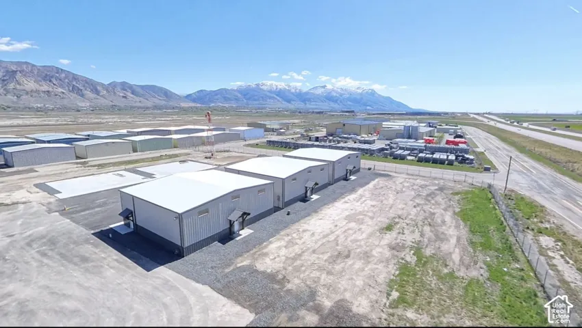 Metal-sided industrial buildings with pitched roofs, surrounded by gravel and paved areas