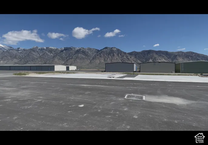 Paved asphalt and concrete surfaces with a storm drain visible in the foreground