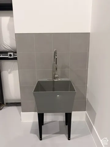 Utility sink with a pull-down sprayer faucet, set against a tiled wall with a painted upper section and white trim