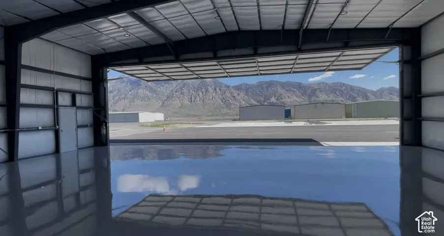 Spacious hangar featuring a large bi-fold door, durable polished concrete flooring, exposed structural beams, and corrugated metal wall panels