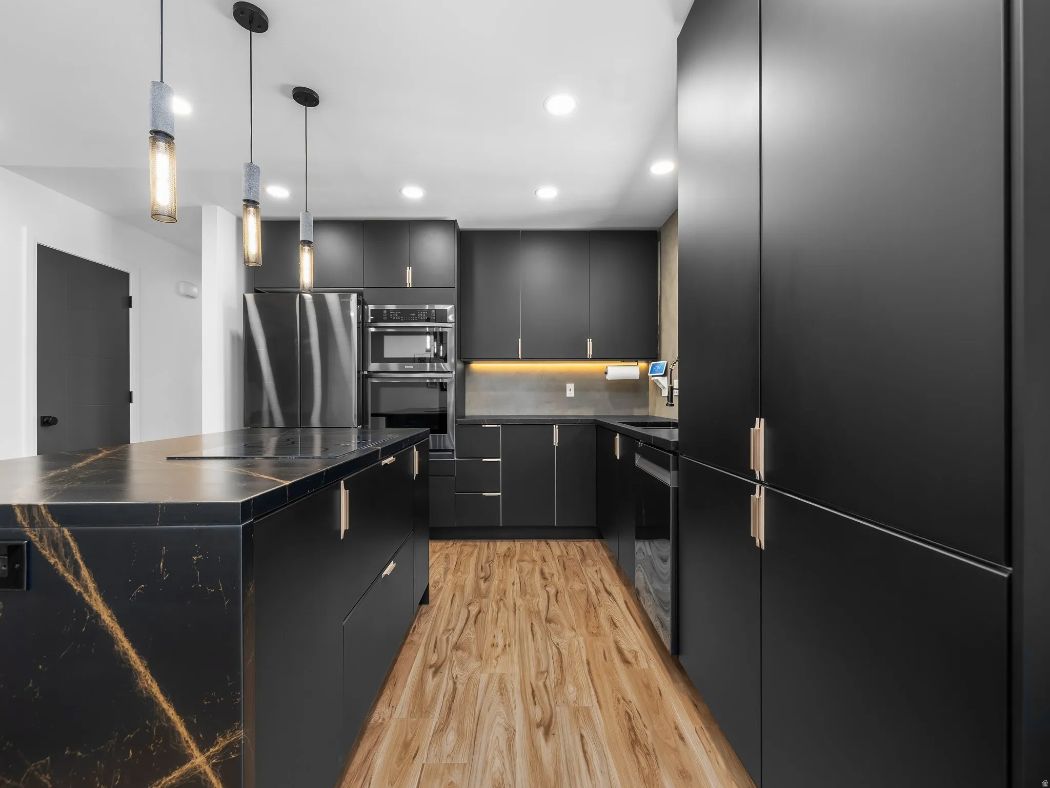 Modern kitchen featuring a waterfall island with black stone countertop and gold veining