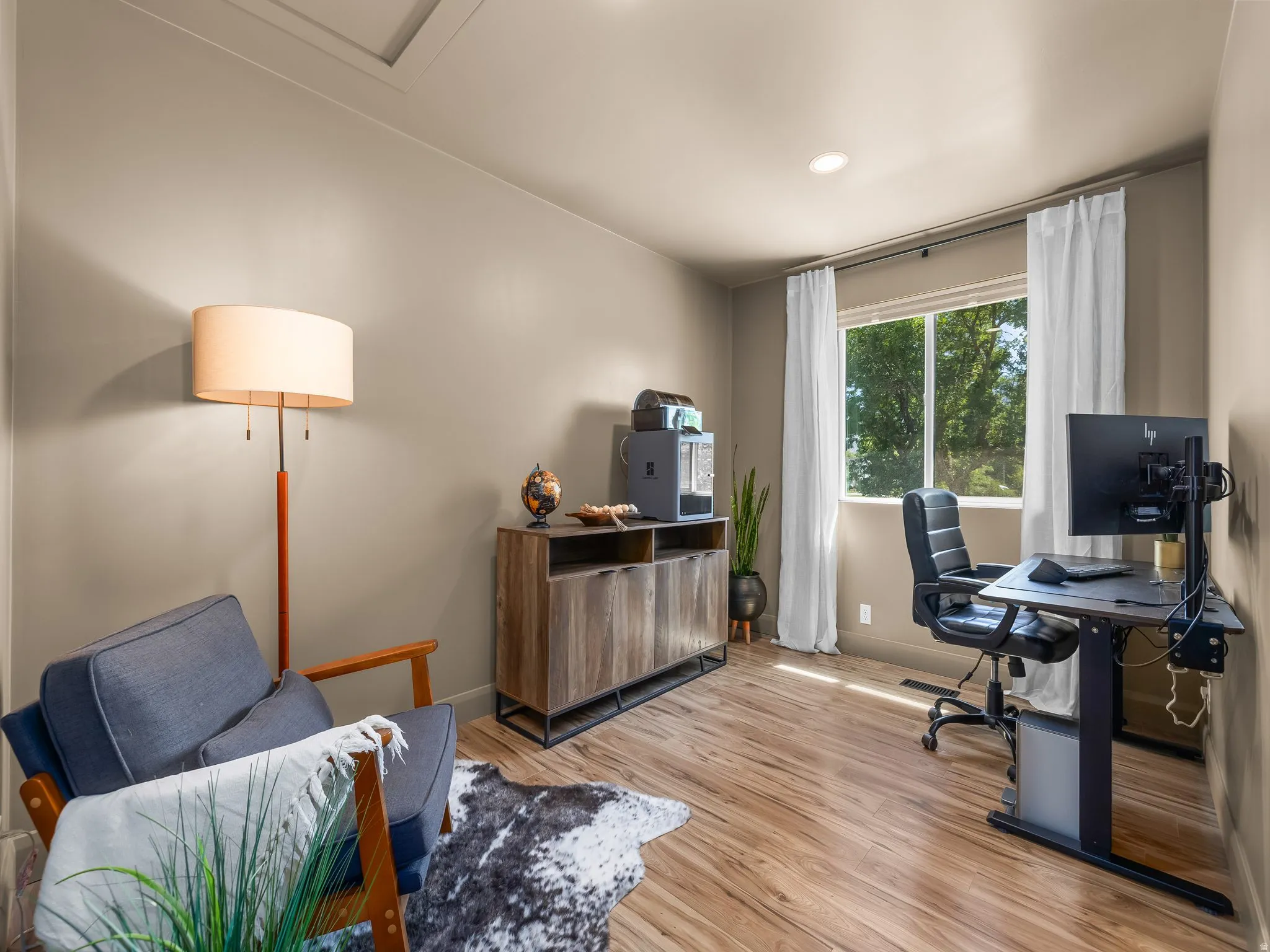 Room featuring wood-finish flooring, recessed lighting, and a large window with white curtain panels