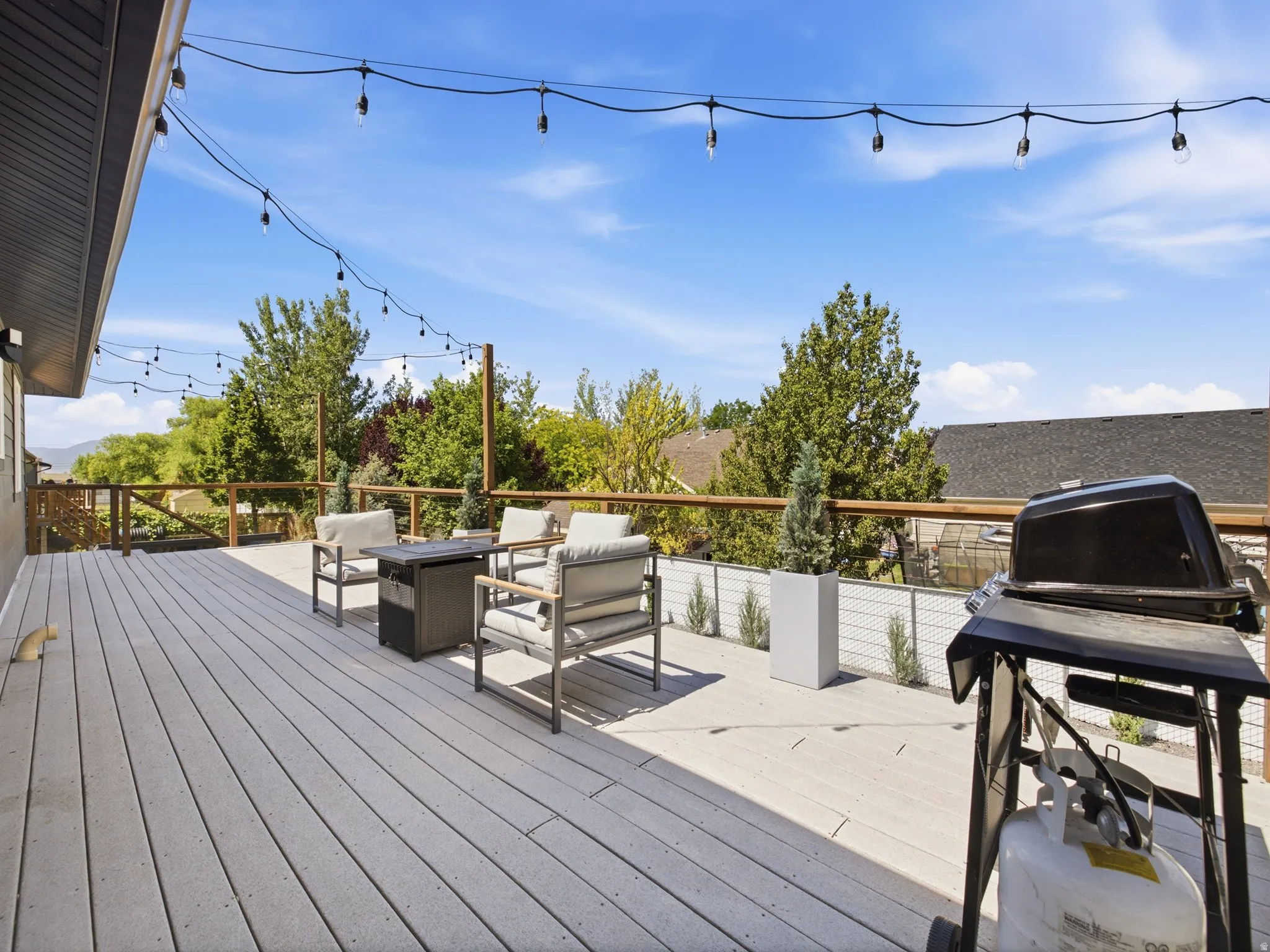 Expansive outdoor deck featuring composite decking, wood railings, and string lighting