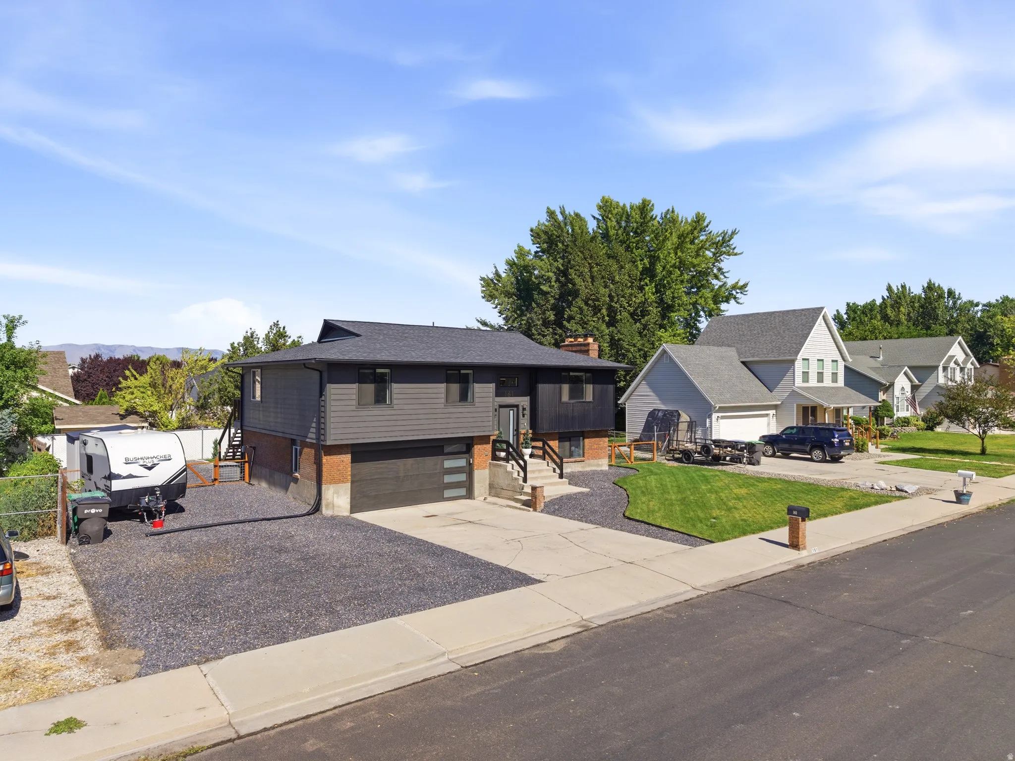 Modern two-story home featuring dark gray siding and a brick base