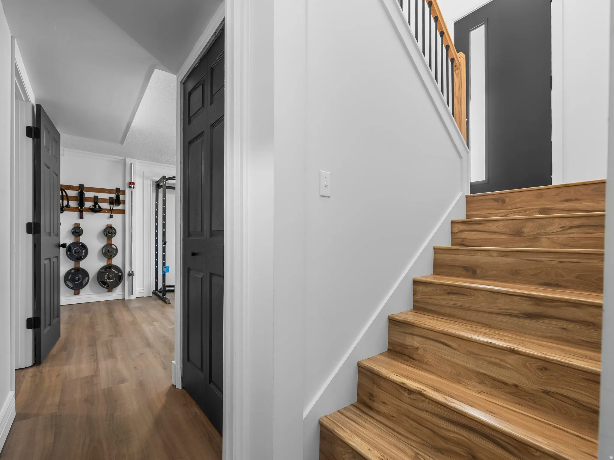 Wood-finish staircase with black balusters and a wood handrail
