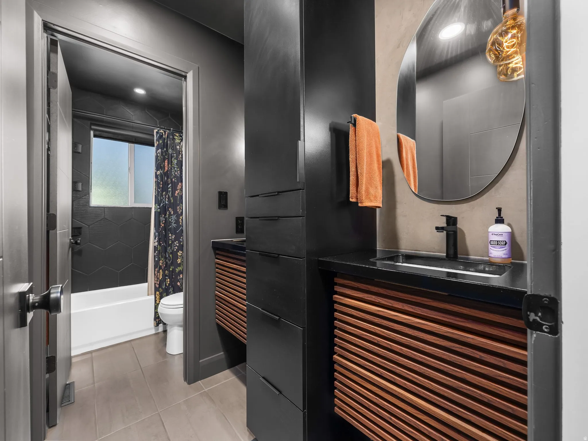 Bathroom featuring a vanity with a dark countertop, an integrated rectangular sink, a black faucet, and slatted wood-finish cabinetry