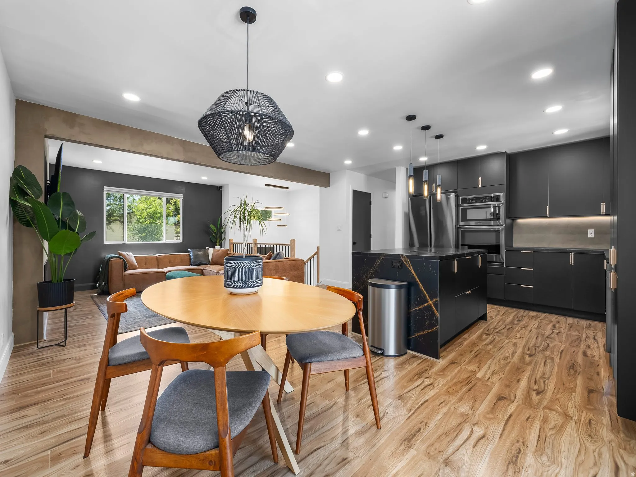Modern kitchen featuring matte black cabinetry, stainless steel appliances, and a central island with a contrasting stone countertop