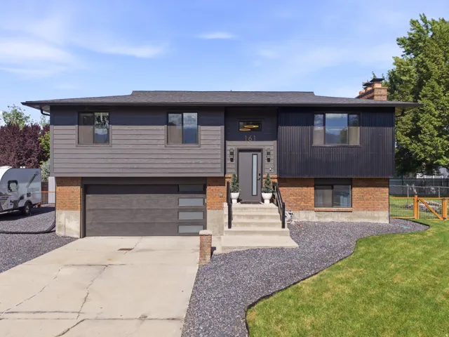 Contemporary facade featuring a dark gray siding, black corrugated metal accents, and a brick base