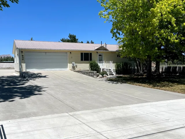 Single-story residence featuring light-colored siding, a metal roof, and an attached two-car garage