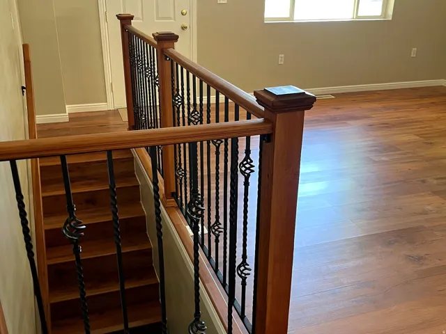 Open-concept area featuring wood-finish flooring, a staircase with wood treads, and an ornate wrought iron and wood railing