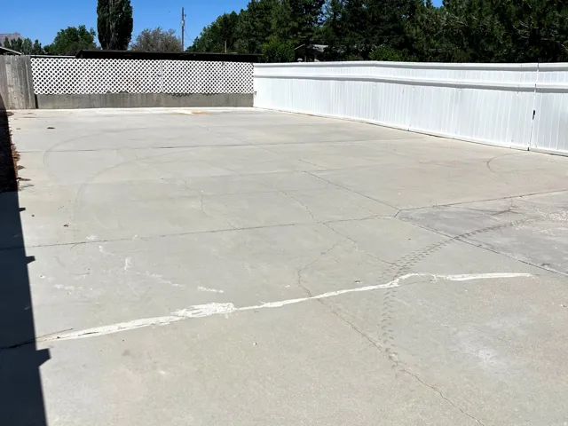 Expansive paved patio area featuring a white privacy fence and a decorative lattice-topped wall