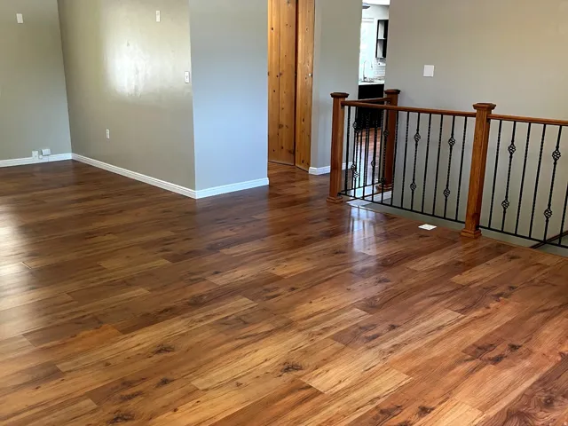 Warm wood-finish flooring extending throughout, complemented by light gray walls and white baseboards