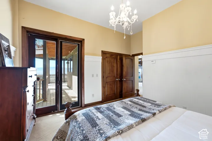 Interior room featuring rich wood-finish french doors opening to an exterior deck, a crystal chandelier, and a wood-finish double-door closet