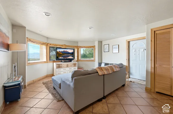 Living area featuring a bay window with natural wood trim, recessed lighting, and tile flooring