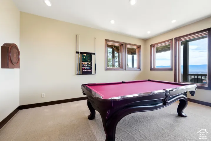 Carpeted room with a pool table, featuring multiple windows with wood trim