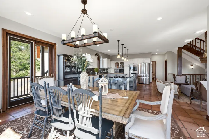 Dining area featuring a rectangular wood-finish table, a dark wood and metal chandelier, and terracotta tile flooring