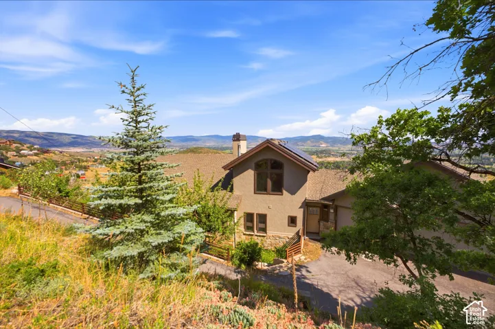 Sloped property featuring a stucco and stone facade, solar panels, and a prominent chimney
