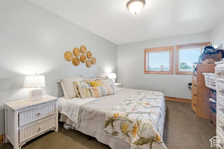 Bedroom featuring light gray walls and two windows with wood trim