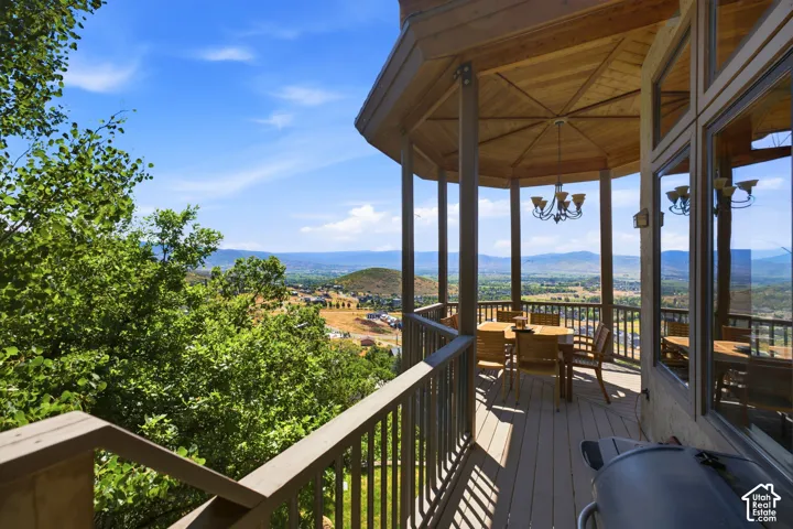 Expansive outdoor deck featuring a gazebo with a wood-finish ceiling, an overhead chandelier, and a surrounding railing system