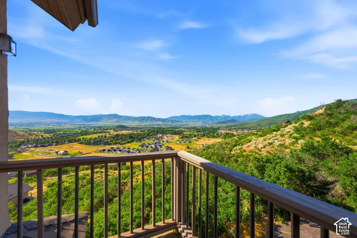 Elevated balcony with a sturdy wood railing, offering expansive landscape scenery including distant mountains and a valley with residential areas