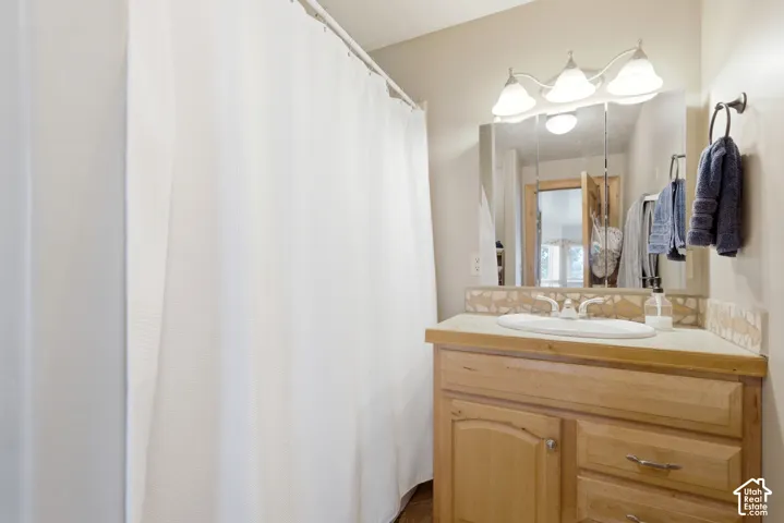 Bathroom vanity with wood-finish cabinetry, a built-in sink, and a decorative tile backsplash