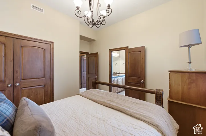 Bedroom featuring a decorative chandelier, recessed ceiling vent, double-door closet with wood-finish doors, and an additional wood-finish door leading to an interior space