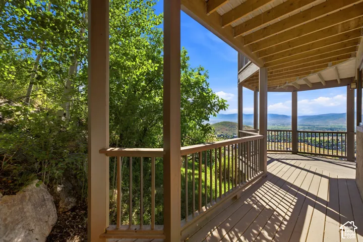 Expansive outdoor deck featuring wood-finish flooring, a wood railing, and structural columns