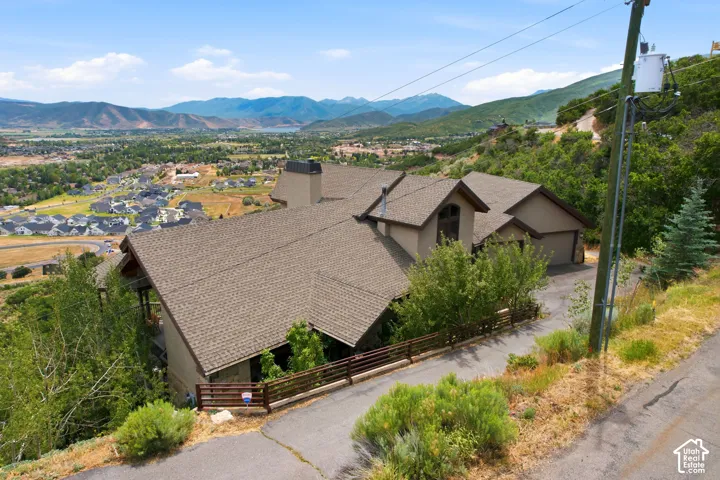 Multi-level hillside residence featuring a two-car garage, multiple gabled roofs, and an upper-level arched window