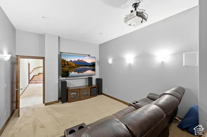 Dedicated entertainment space featuring a wall-mounted television, recessed ceiling lighting, a ceiling-mounted projector, and wall sconces providing ambient illumination