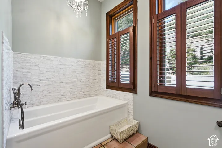 Freestanding soaking tub with an antique-style faucet, complemented by a stacked stone tile surround